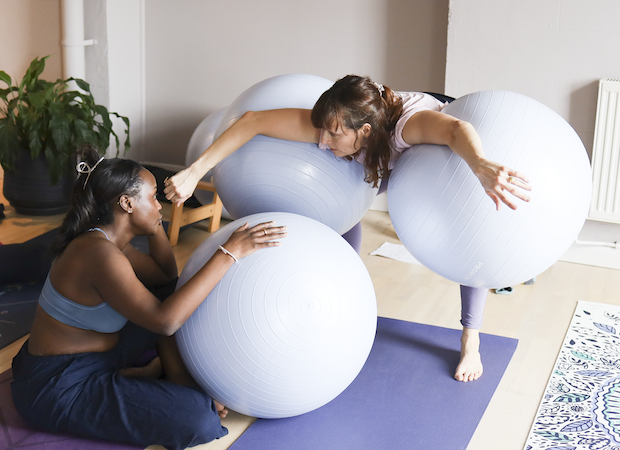 Charli Van Ness and a student chatting during a session on backbending using balls as a prop