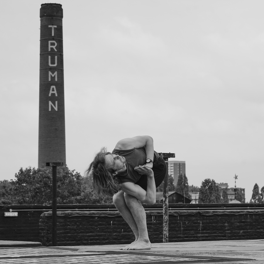 Daniel Simpson practicing a yoga pose similar to Revolved Chair Pose
