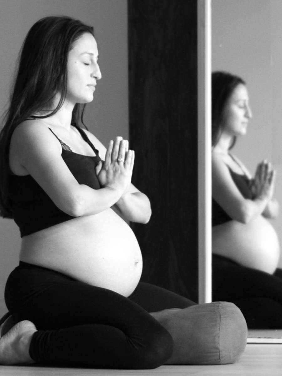 A pregnant student practicing yoga to support physical and mental well-being during a pregnancy yoga teacher training